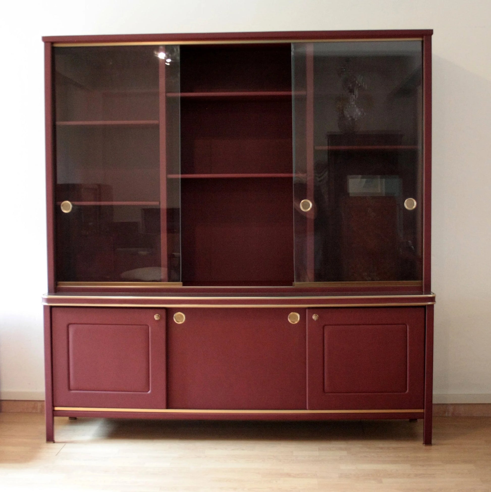 Credensa o libreria a due corpi rivestita in similpelle bordeaux con ante scorrevoli in vetro design italiano d’epoca umberto mascagni negli anni 50
