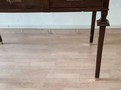 Gambe in legno noce stile impero con piedini in ottone su pavimento in legno della scrivania vintage stile impero